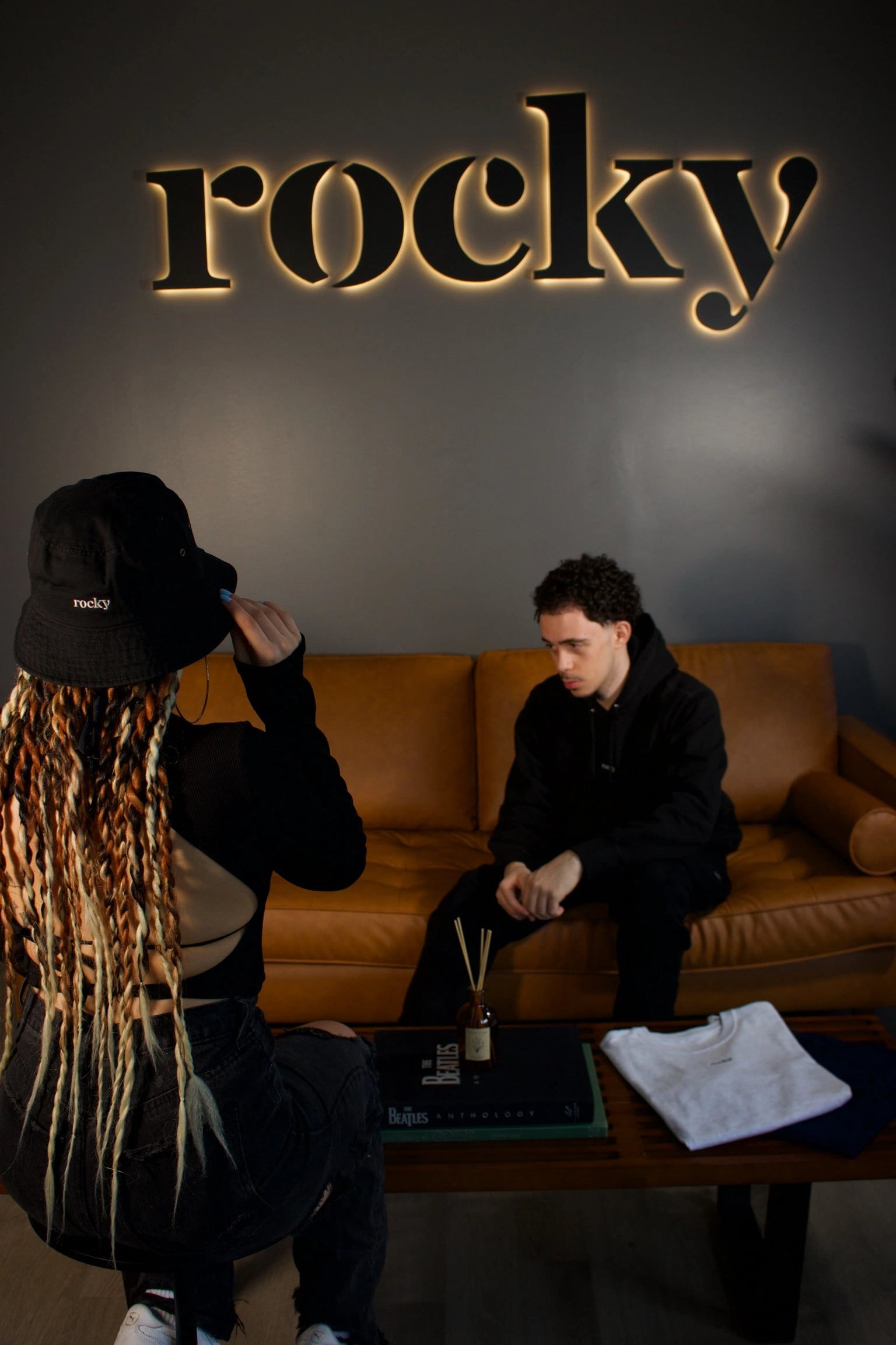 Person with braided hair sitting at table with white shirt