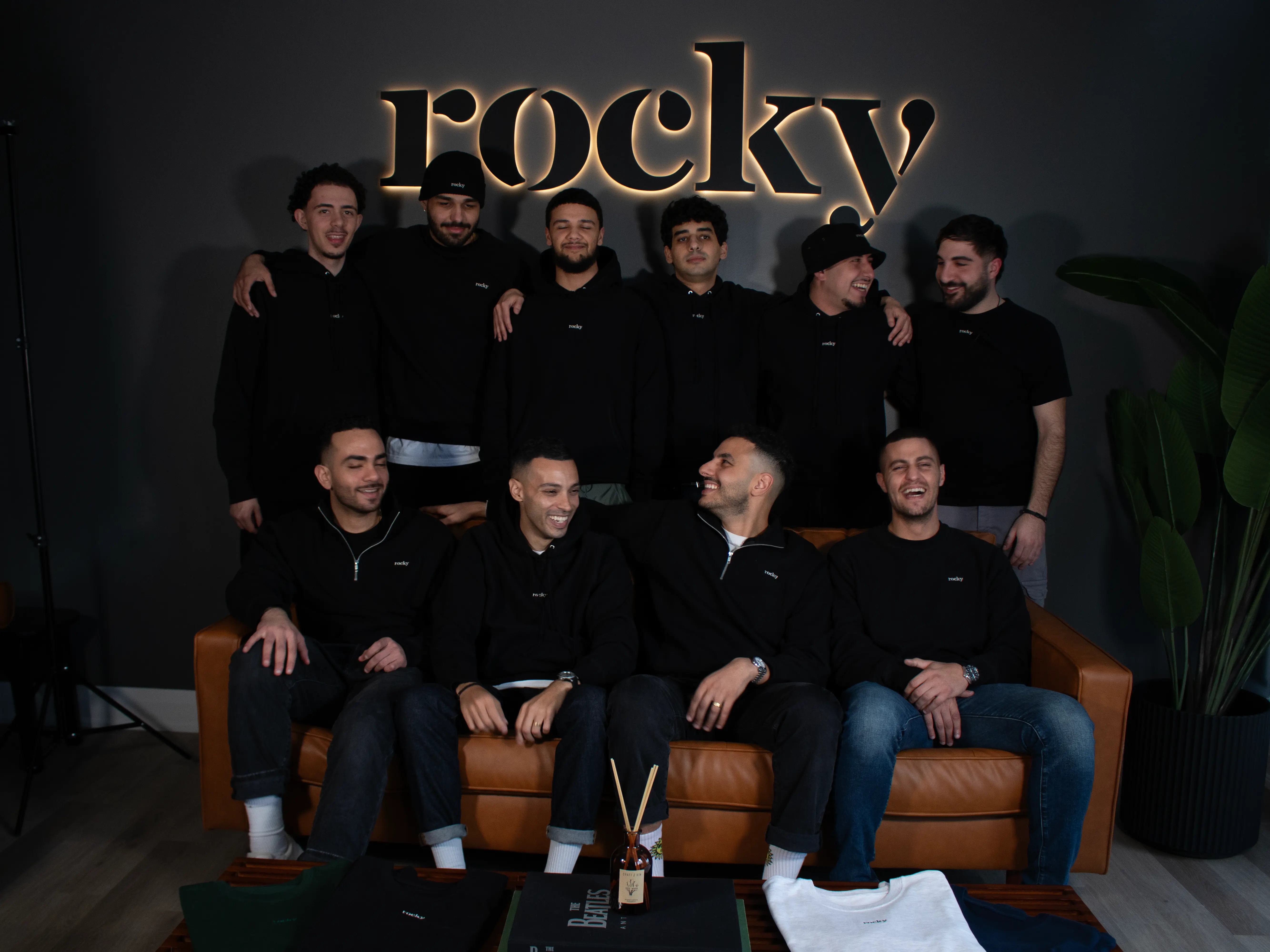 Group of men in black hoodies with illuminated ROCKY sign