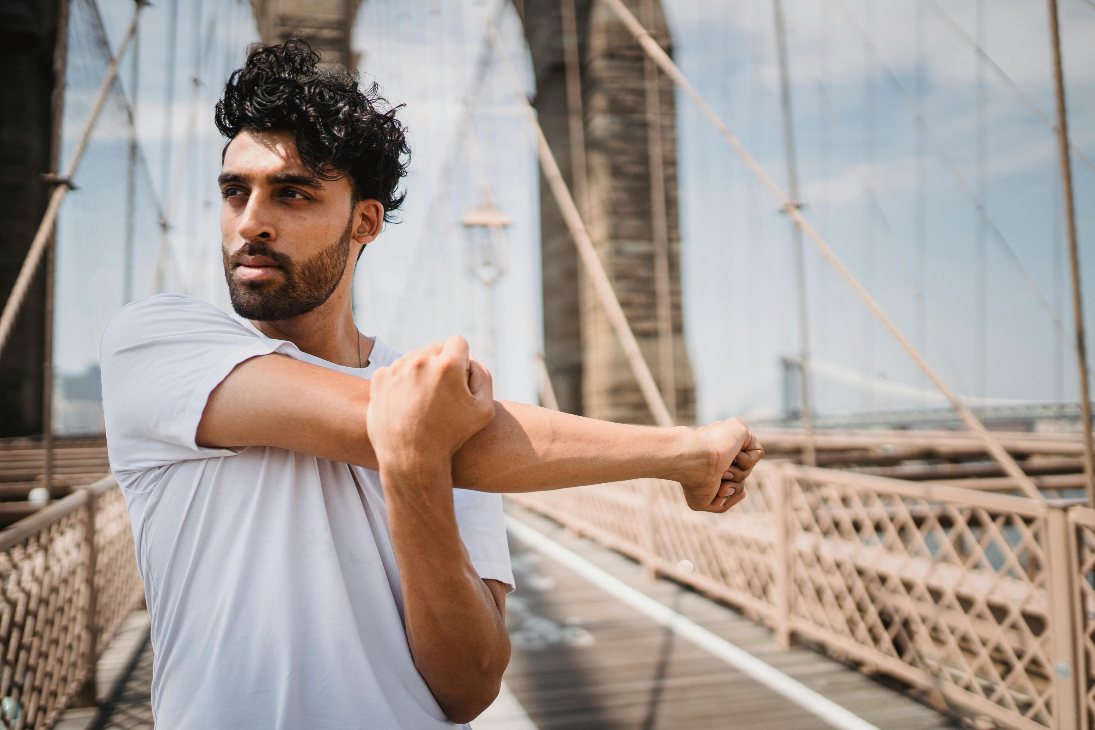 Man stretching outdoors on a bridge